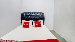 Uma cama de solteiro com colchão branco e duas almofadas vermelhas com a marca 'OYO'.