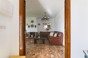 A living room with a fireplace, a sofa, a coffee table, and a chandelier. - A&N Diamante, Valle Niza (Benajarafe)