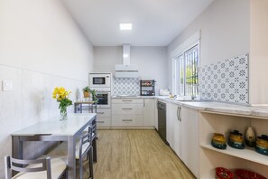 Eine kompakte Küche mit Essbereich, ausgestattet mit Mikrowelle, Backofen und kleinem Kühlschrank.