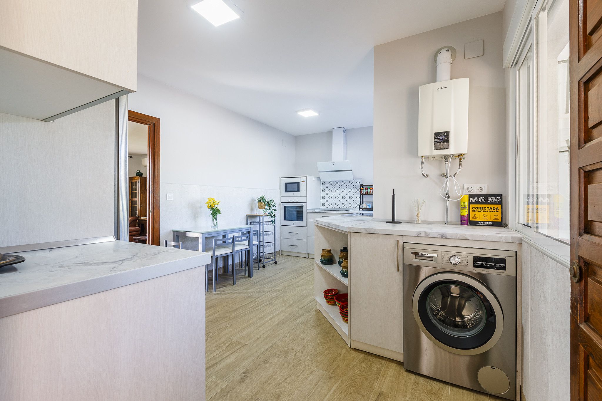 A modern kitchen with a built-in washing machine, a dining area with chairs, and a kitchen island.