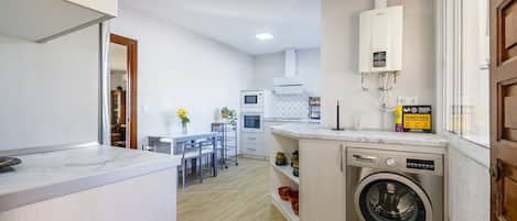A modern kitchen with a built-in washing machine, a dining area with chairs, and a kitchen island.
