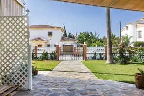A stone pathway leading to a gated entrance with a white fence and decorative elements. - A&N Diamante, Valle Niza (Benajarafe)