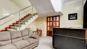 Habitación de hotel con escalera, sofá, mueble y un cartel que indica servicios de la empresa.