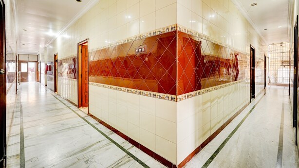 Un pasillo con pared y piso de baldosas, y una puerta.