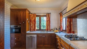 A kitchen with wooden cabinets, a built-in oven, a dishwasher, a sink, and a stove. - Villa MAR DE LUR by Abahana Villas (Calpe / Calp)
