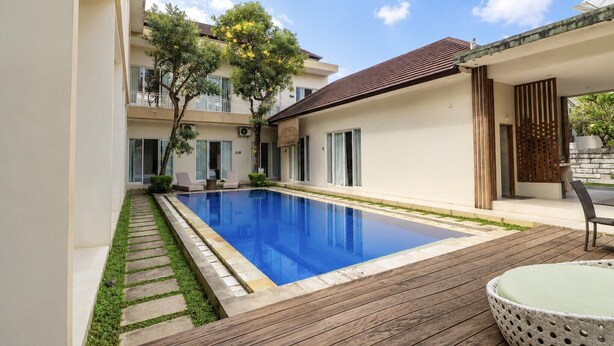 A modern residential building with a swimming pool, wooden deck, and outdoor seating area. - Cozy Deluxe Stay at The Vinhill Studio (Bali)