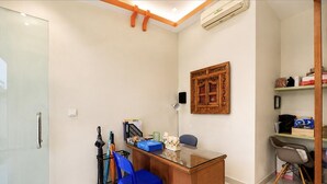 Una habitación con escritorio, silla y una estantería en la pared con varios objetos.