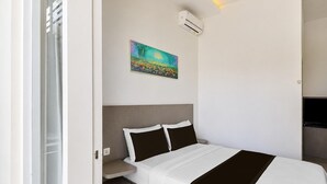 Una habitación de hotel con cama, un cuadro, un equipo de aire acondicionado y una televisión.