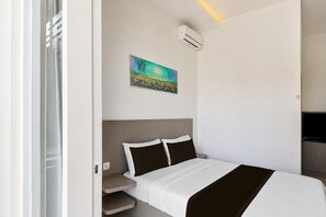 Una camera d'albergo con un letto, un quadro, un condizionatore d'aria e una televisione.