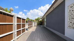 A pathway leading to a building with a wooden fence on one side and a wall with a decorative panel on the other. - Pool Access Suite at The Vinhill Studio (Bali)