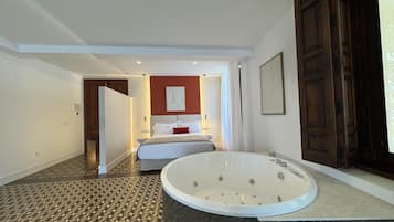 Habitación de hotel con una bañera grande, una cama y una pared decorada en rojo.