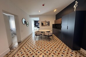 A modern kitchen with dark cabinetry, a round dining table with chairs, and a patterned floor.