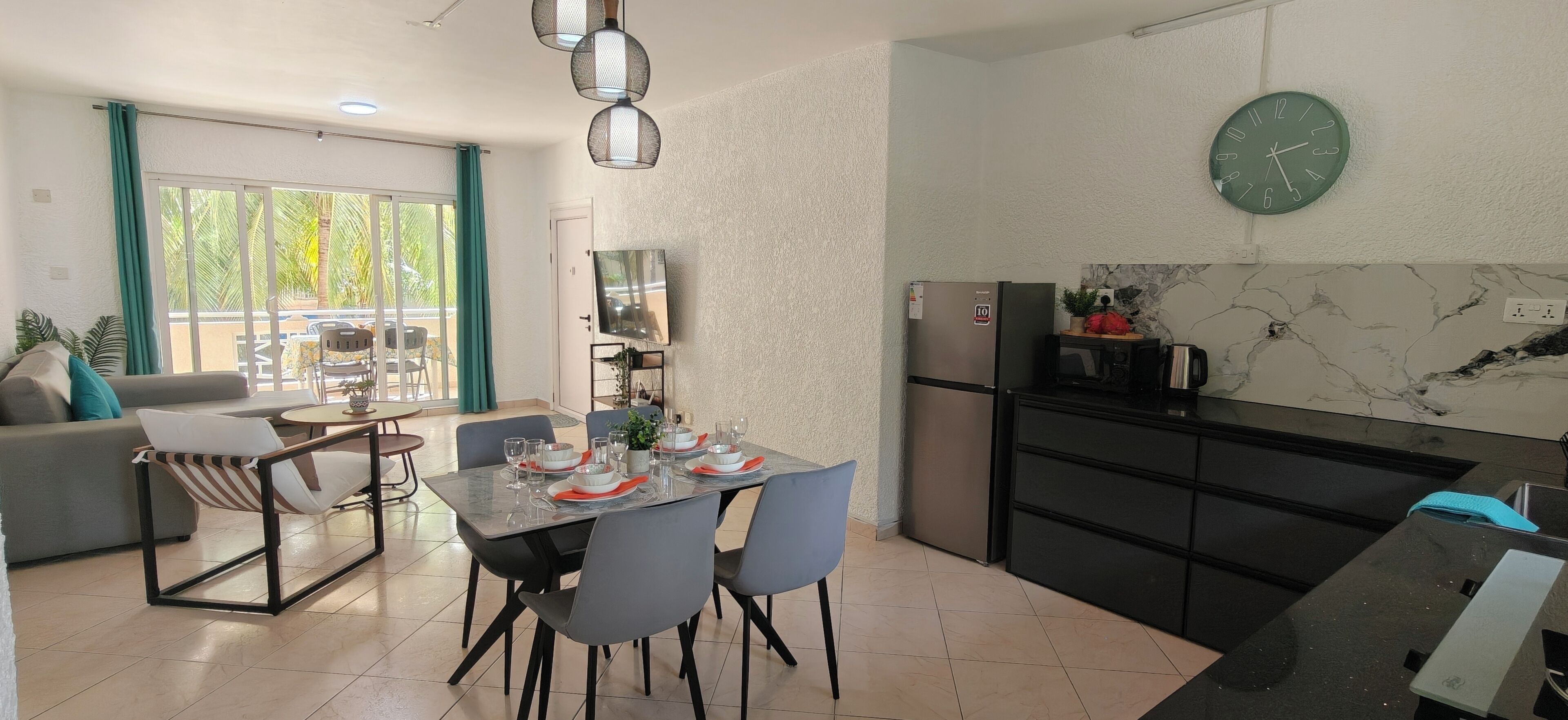 Una cucina moderna con zona pranzo, televisione a schermo piatto e una sveglia appesa al muro.