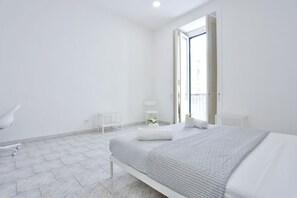 Une chambre moderne avec un grand lit, une petite table de chevet, une chaise et une fenêtre donnant sur un beau paysage.