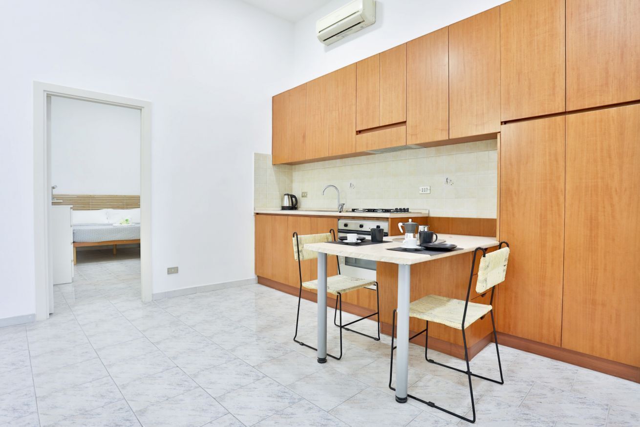 A compact kitchen with wooden cabinets, a white countertop, and a small dining table with chairs.