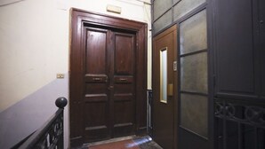 Uma porta dupla de madeira com puxador de metal, um portão de metal com fechadura e um pequeno objeto retangular na parede.