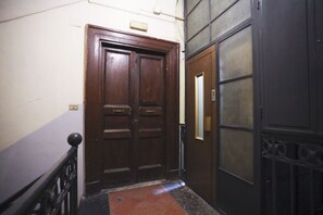 A wooden double door with a metal handle, a metal gate with a keyhole, and a small rectangular object on the wall. - A comfortable and large apartment ideal for four guests and strategically located in the heart of Naples, allowing you to fully experience the city's authentic atmosphere; it is just steps away from Piazza del Plebiscito and the entrance to the evocative (Napoli)