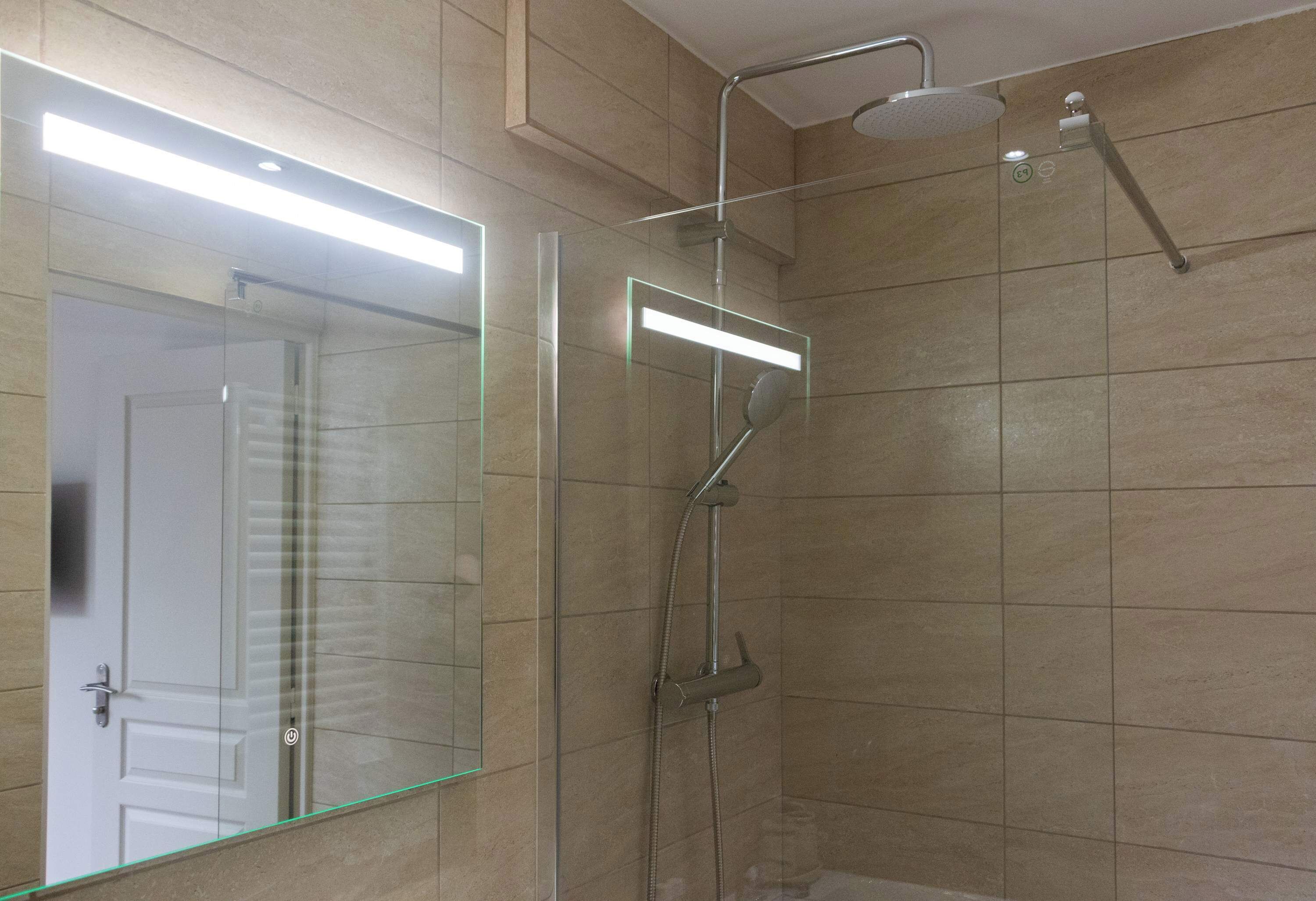 Une salle de bain dotée d’une douche à parois de verre, d’un pommeau de douche à main et d’un robinet mural.