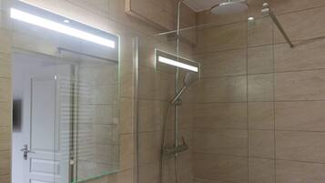 Une salle de bain dotée d’une douche à parois de verre, d’un pommeau de douche à main et d’un robinet mural.