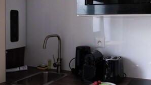 Eine kompakte Küche mit Spüle, Kaffeemaschine, Toaster und einem Teller mit Speisen.