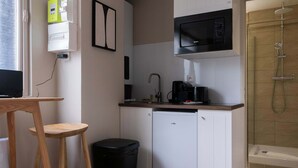 Eine kompakte Küchenzeile mit Mikrowelle, Kaffeemaschine und kleinem Kühlschrank.