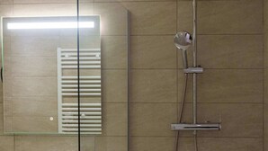 Ein modernes Badezimmer mit Duschkabine aus Glas, einem weißen Waschbecken und einem Spiegel.