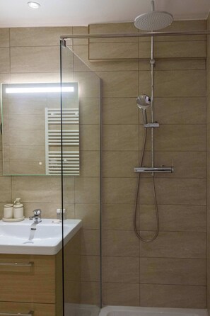 A modern bathroom with a glass shower enclosure, a white sink, and a mirror. - Studio parisien cosy, proche Opéra/Saint-Lazare (Paris)