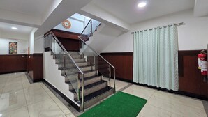A hotel lobby with a staircase, a fire extinguisher, and a green carpet. - Shimla PineCrest Retreate (Shimla)