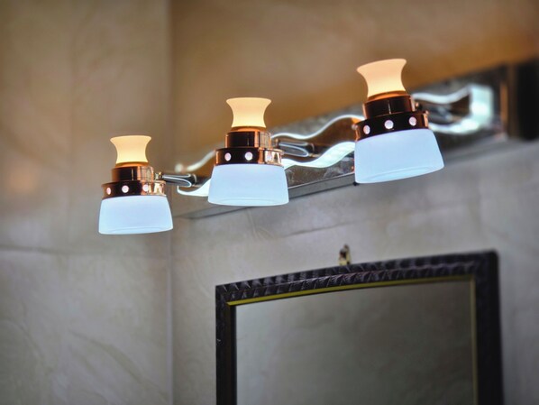 Un bagno con uno specchio e tre luci a parete.