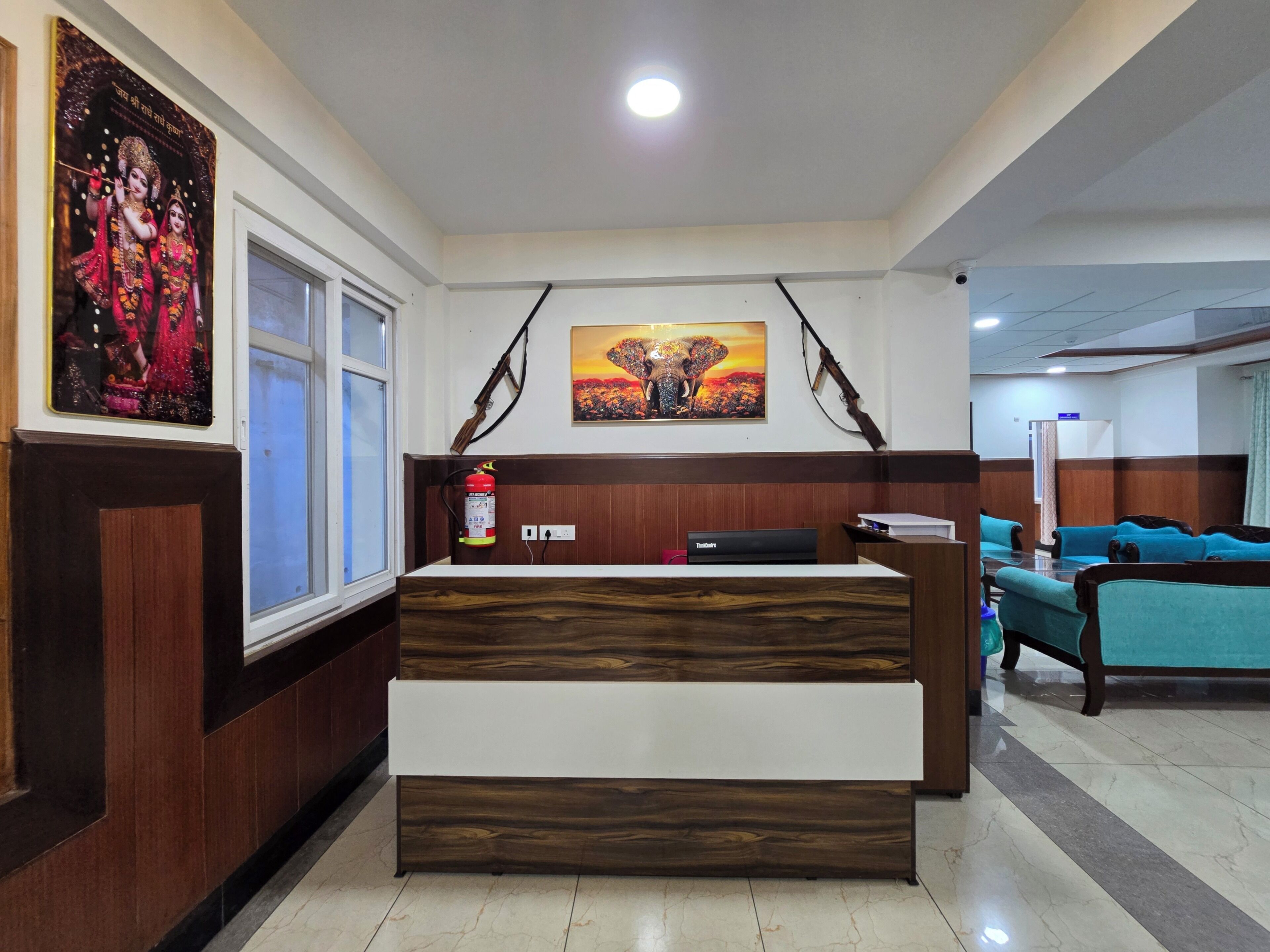 A reception desk with a modern design, flanked by a window and a wall-mounted elephant painting.