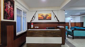 A reception desk with a modern design, flanked by a window and a wall-mounted elephant painting.