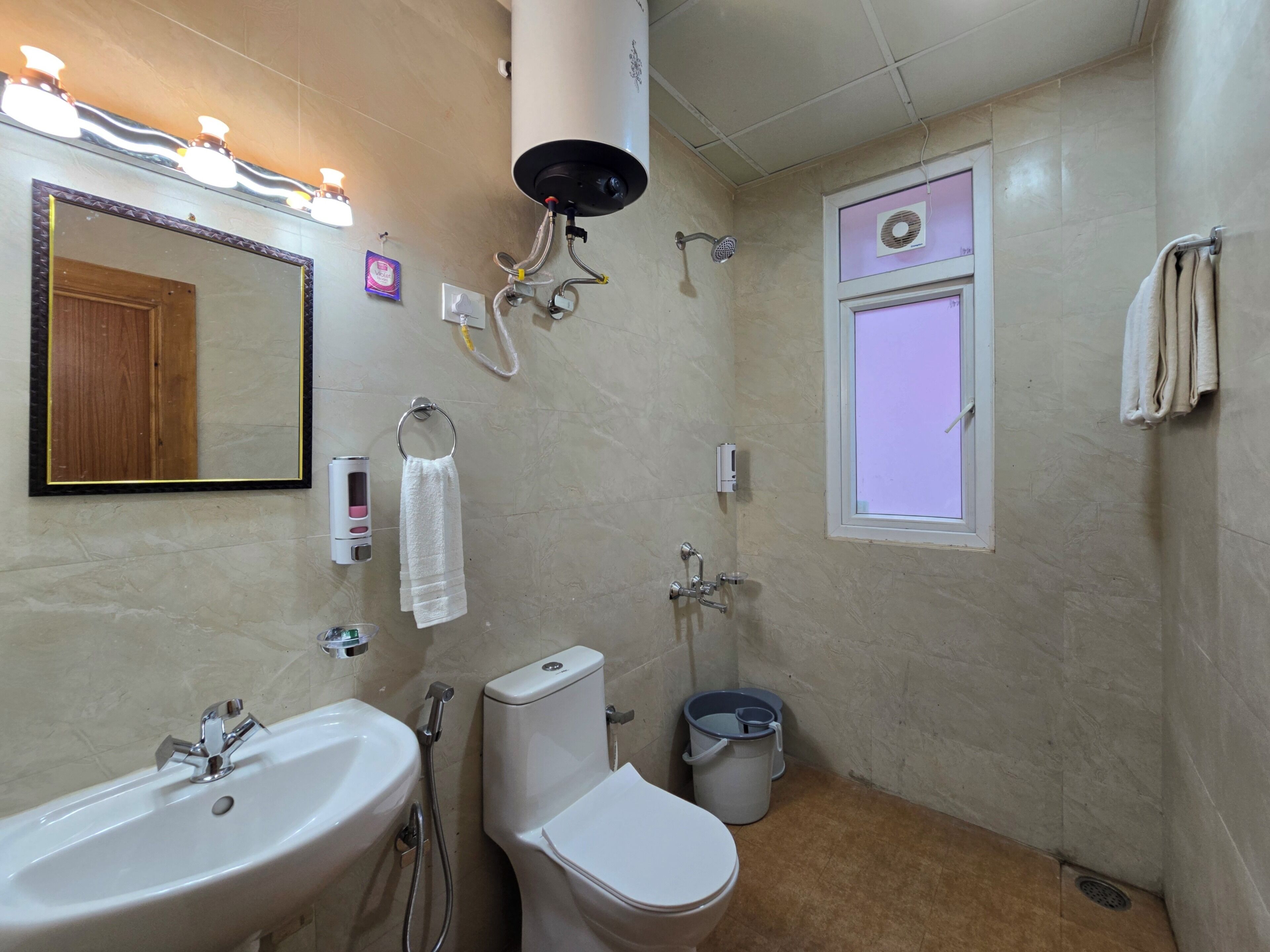 A bathroom with a sink, toilet, shower, and a mirror.