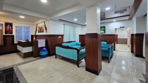 A hotel lobby with a reception desk, seating area with sofas, and a corridor leading to other rooms. - Shimla PineCrest Retreate (Shimla)