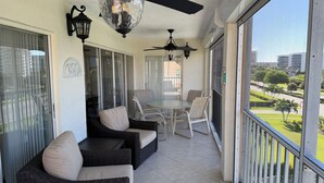 A covered outdoor area with wicker furniture, ceiling fans, and a view of a park. - Oceanside Marco Island Retreat: Expansive Views of Sunset, Pool & Beach (Marco Island)