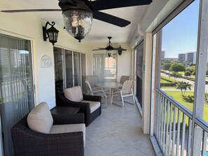 A covered outdoor area with wicker furniture, ceiling fans, and a view of a park. - Oceanside Marco Island Retreat: Expansive Views of Sunset, Pool & Beach (Marco Island)