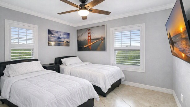 A bedroom with two beds, a ceiling fan, and a large window with blinds. - Oceanside Marco Island Retreat: Expansive Views of Sunset, Pool & Beach (Marco Island)