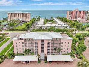 A hotel with multiple floors, a central courtyard, and a view of the ocean. - Oceanside Marco Island Retreat: Expansive Views of Sunset, Pool & Beach (Marco Island)