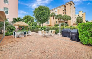 Un patio con mobiliario exterior, una parrilla cubierta y un gran paraguas.
