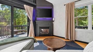 Un salon moderne doté d’une cheminée, d’un téléviseur à écran plat et d’un coin salon confortable.