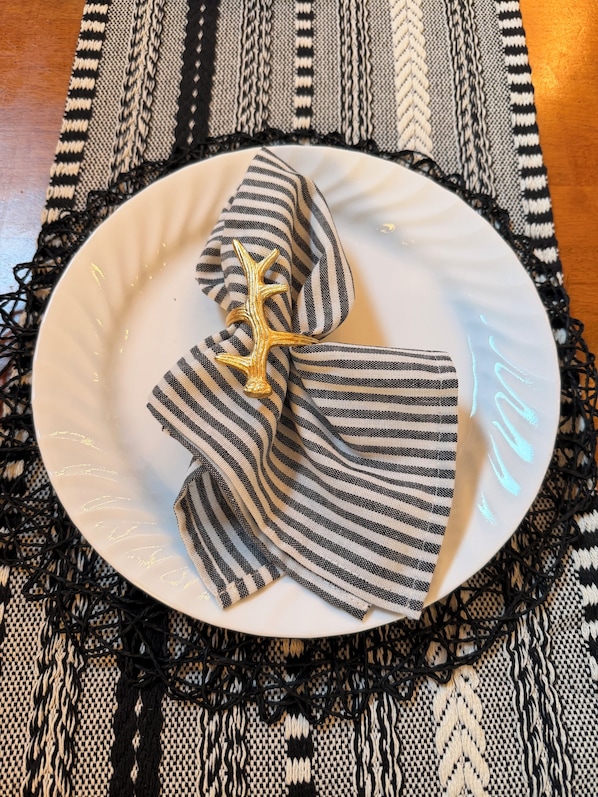 A white plate with a black and white striped cloth and a golden star-shaped object on a woven placemat.