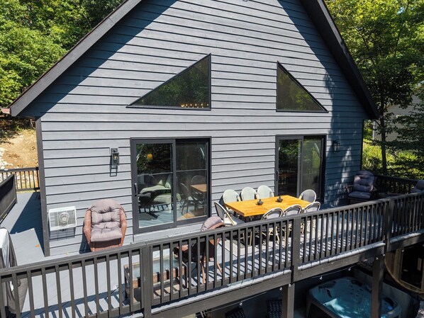 A modern house with a deck, outdoor seating, and a hot tub.