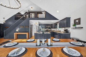 A modern kitchen with dark cabinetry, a central island, and a dining area with a wooden table and striped placemats.