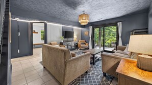 Een moderne woonkamer met een bank, fauteuils, een salontafel en een televisie.