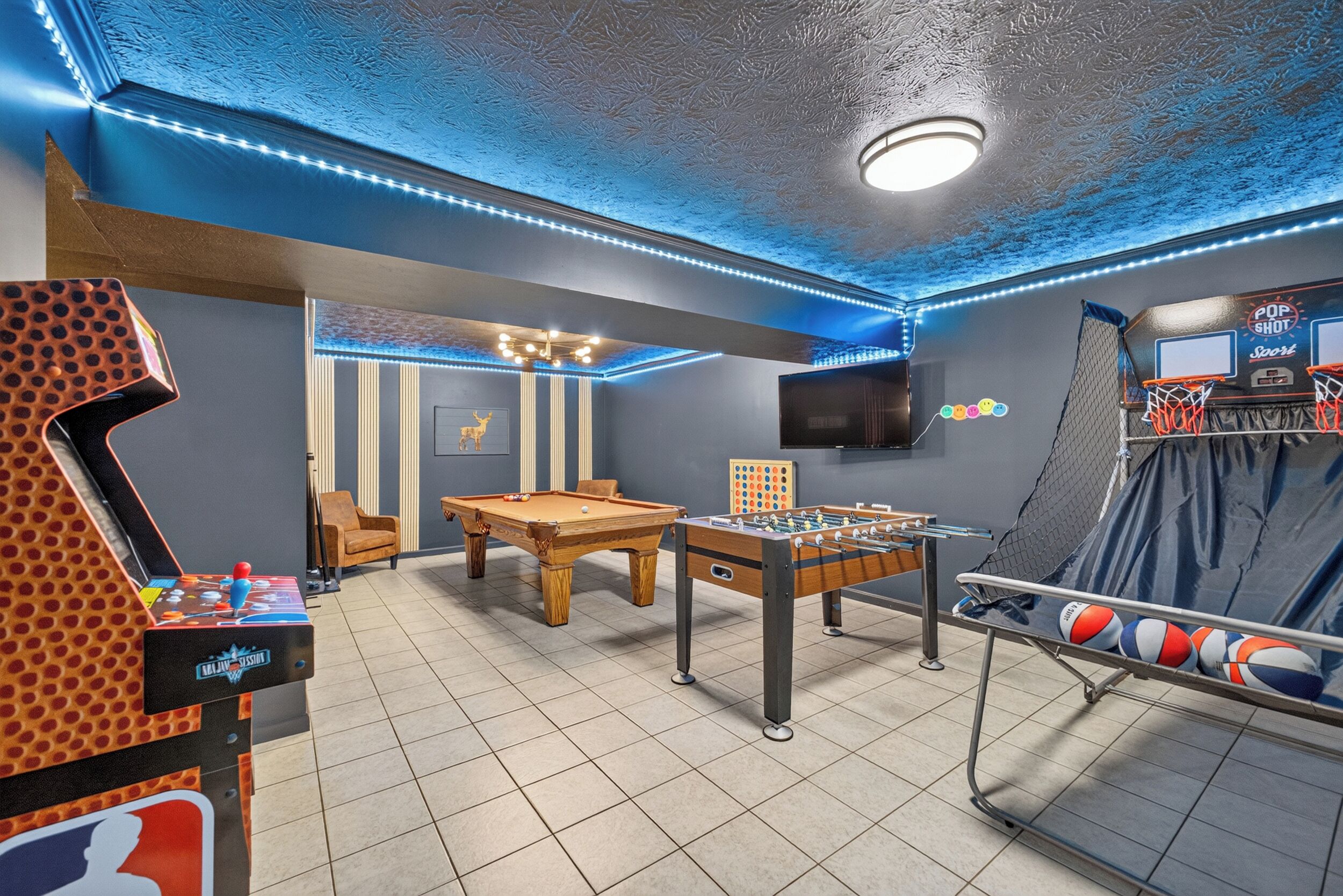 Une salle de loisirs équipée d’un baby-foot, d’une table de billard et d’un panier de basket.