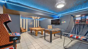 Une salle de loisirs équipée d’un baby-foot, d’une table de billard et d’un panier de basket.