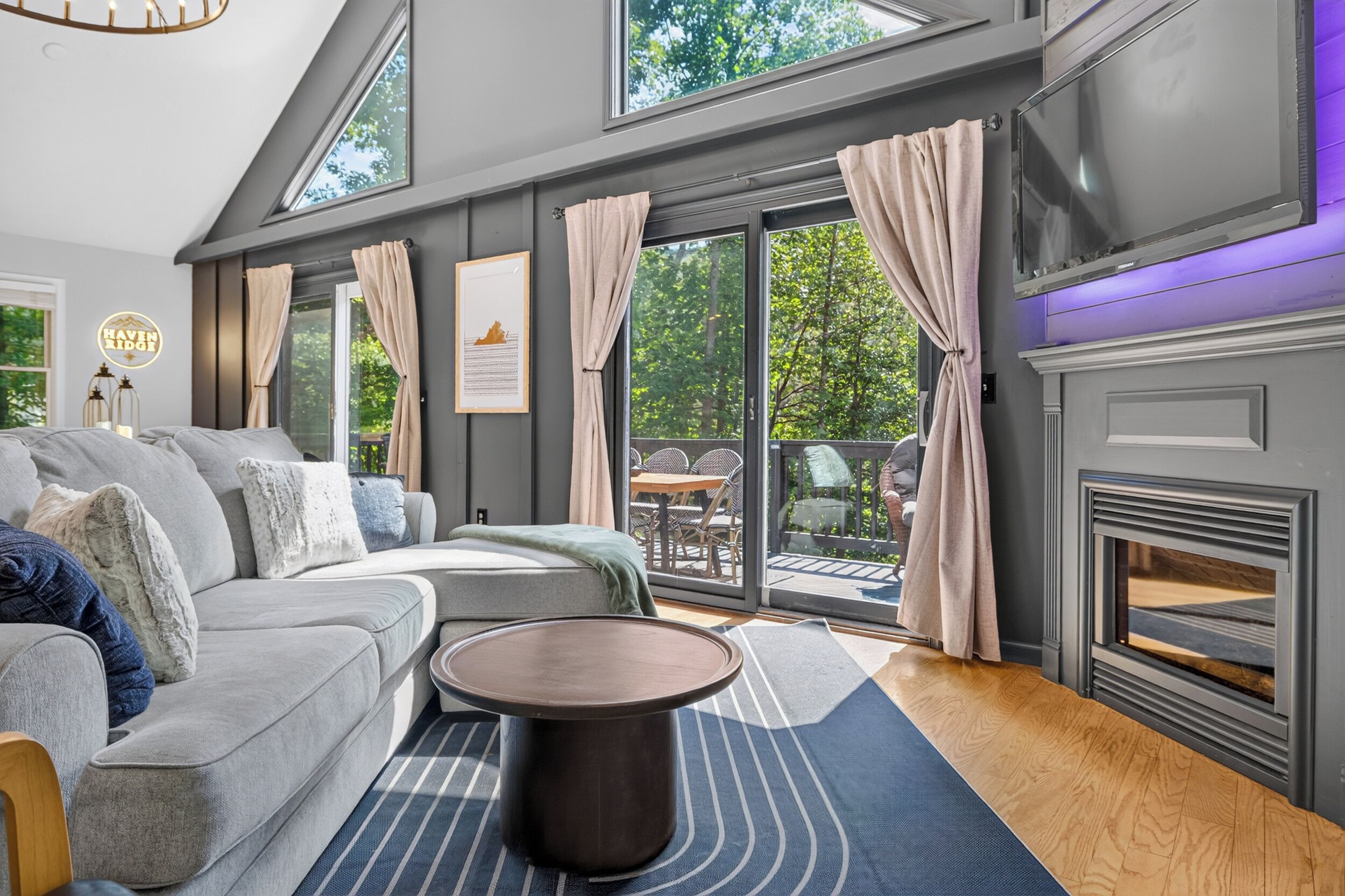 Ein modernes Wohnzimmer mit einem grauen Sofa, einem runden Couchtisch und einem Kamin.