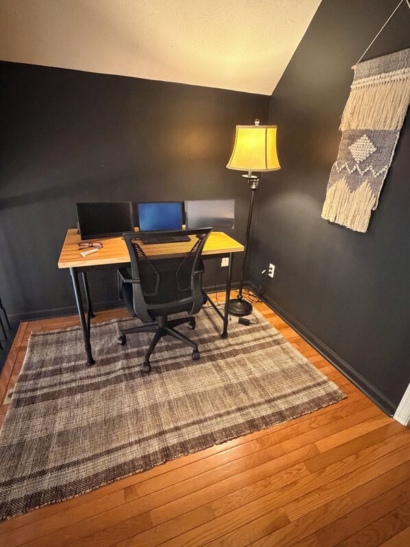 Un petit bureau comprenant un bureau, deux chaises, un ordinateur et une lampe.
