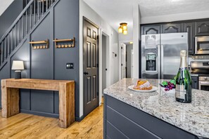 A modern kitchen with a marble countertop, a bottle of champagne, and a wooden bench.