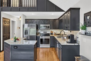 A modern kitchen with dark cabinetry, stainless steel appliances, and a granite countertop.