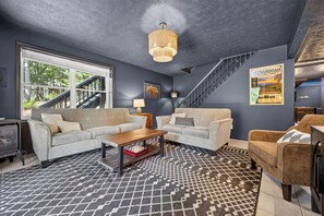 A modern living room with a sofa, armchairs, a coffee table, and a patterned rug.